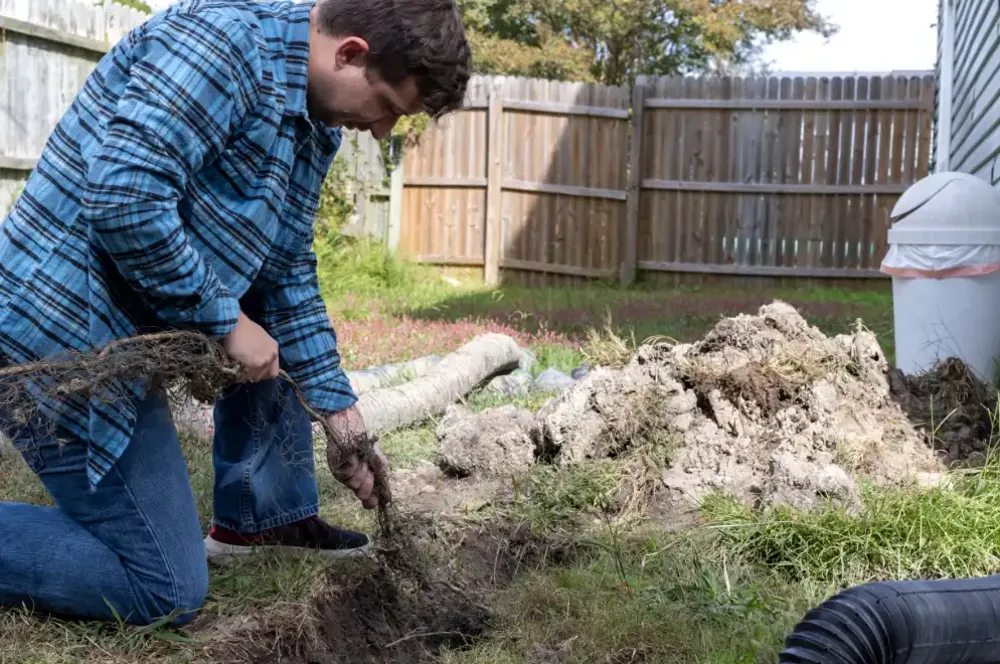 Worker accessing a drainage trench near a home